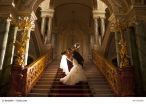 Ein glückliches Brautpaar auf steigt die Treppe zur Hochzeit hinauf - Bild: denisfilm - fotolia.com